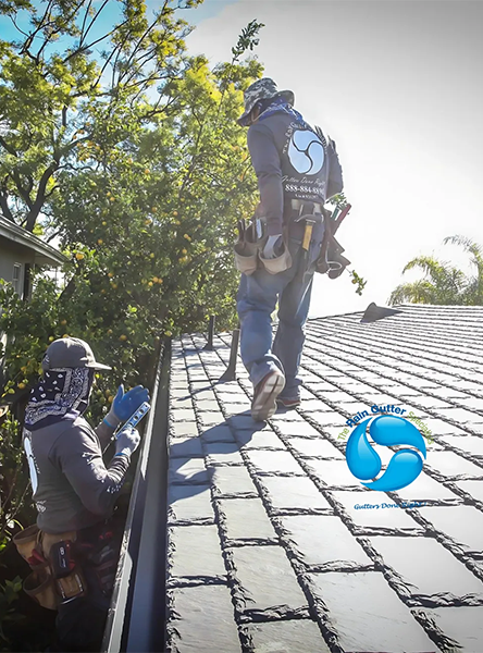 Rain gutter installation team working on a Malibu home roof